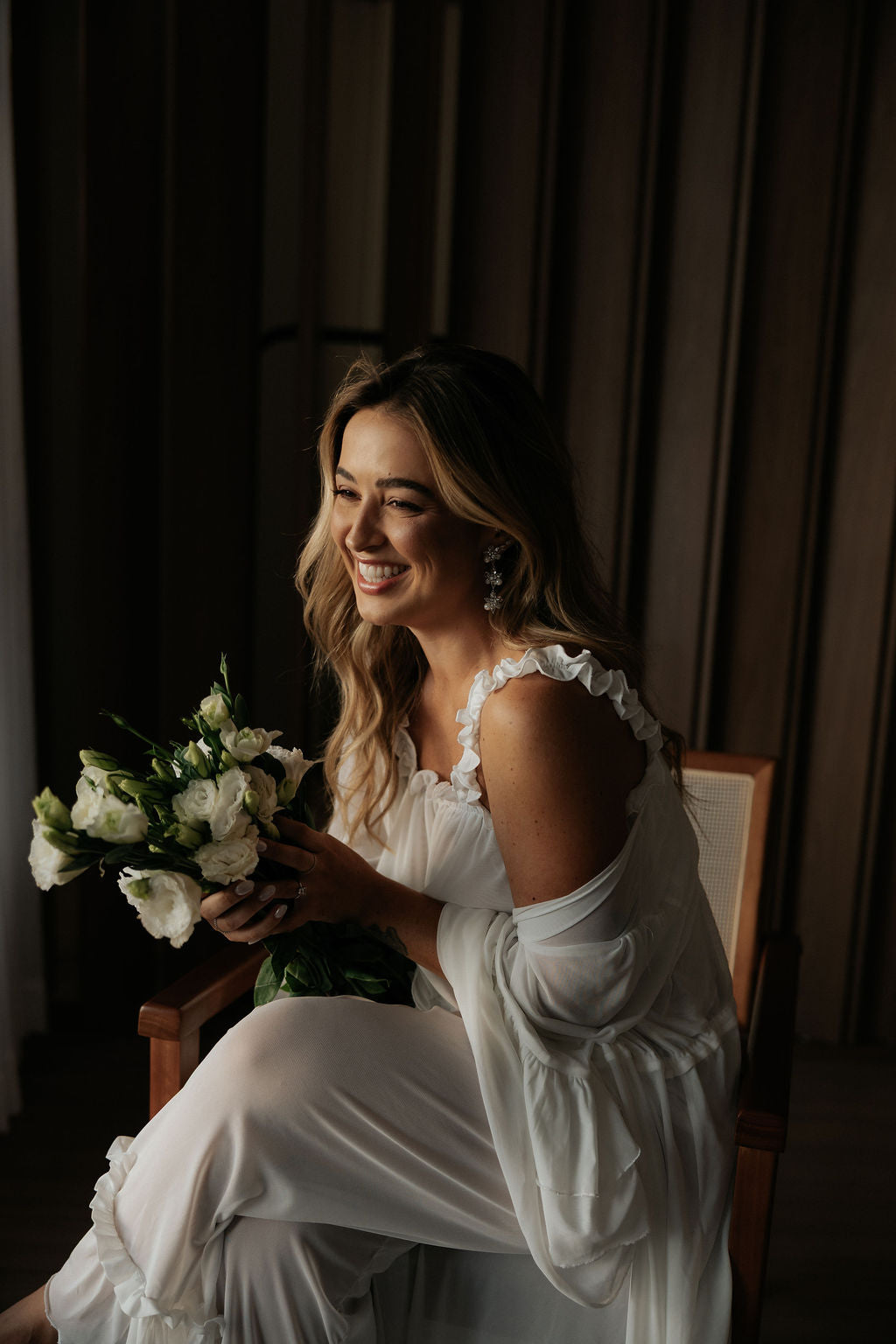 Noiva sorrindo com um buquê de flores brancas