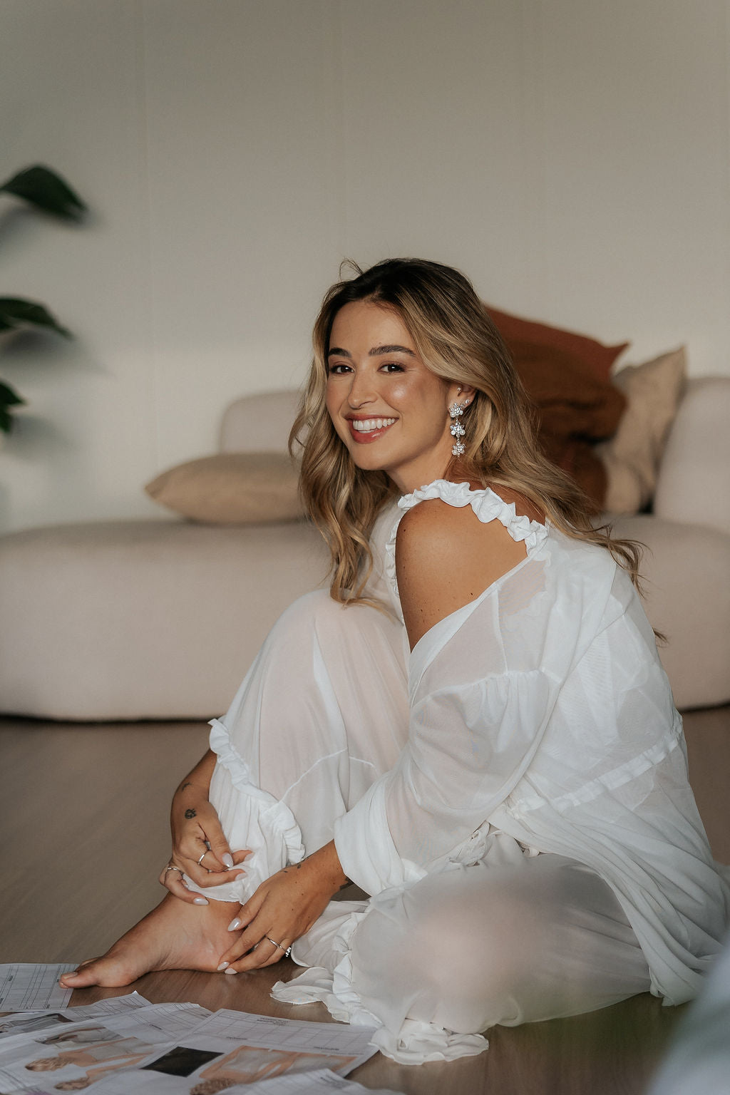 Noiva sentada no chão sorrindo, com robe de tule