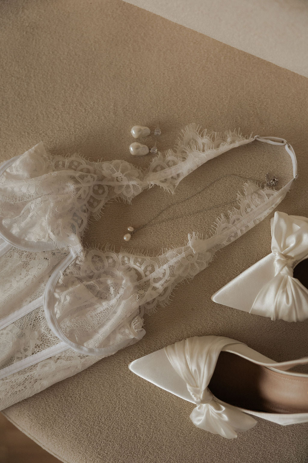 Corset de renda, sapatos de cetim com laço e brincos de pérola